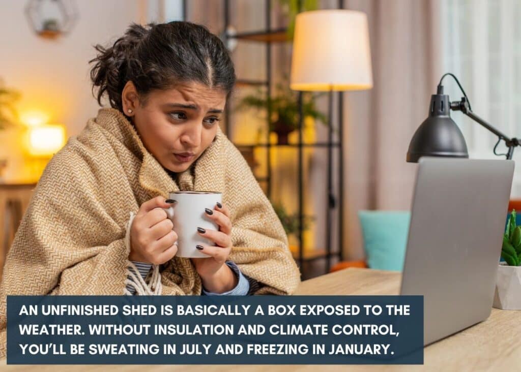 woman wrapped in a blanket holding a mug and looking at her computer